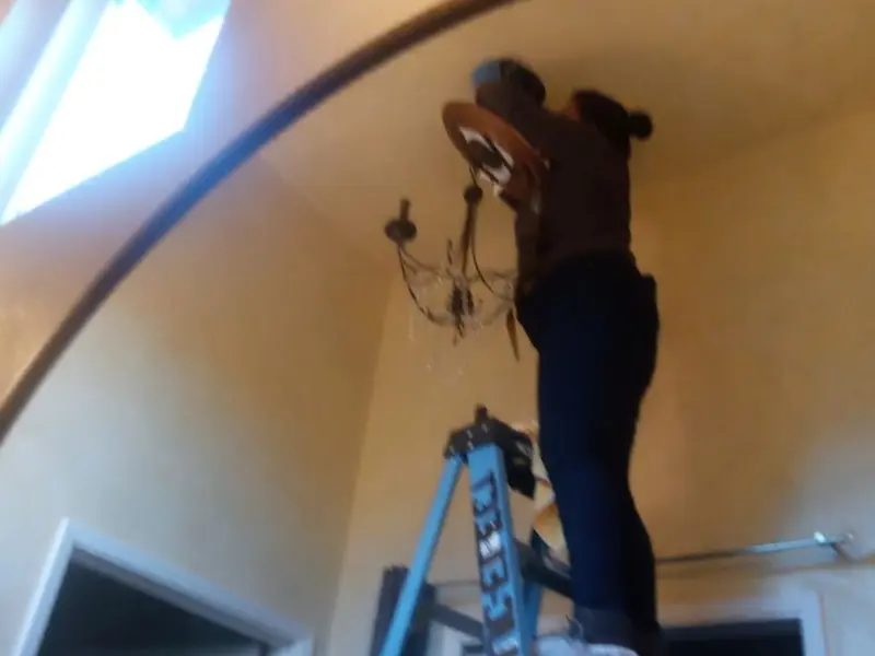Electrician installing a chandelier in a Chowchilla residence